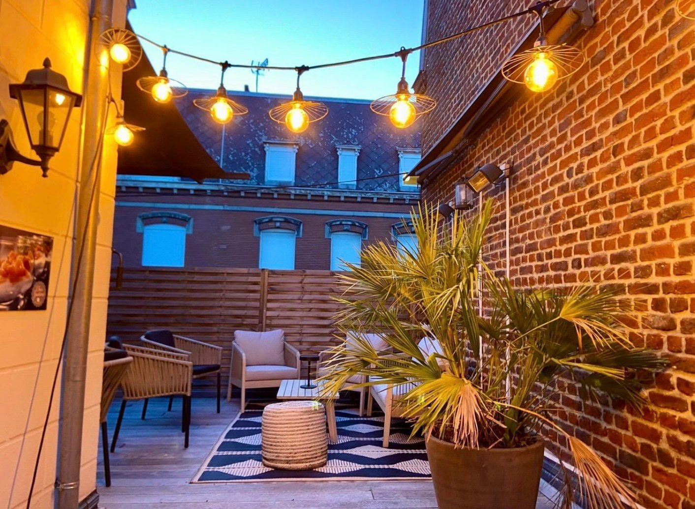 Terrasse en briques, guirlandes lumineuses et salon de jardin